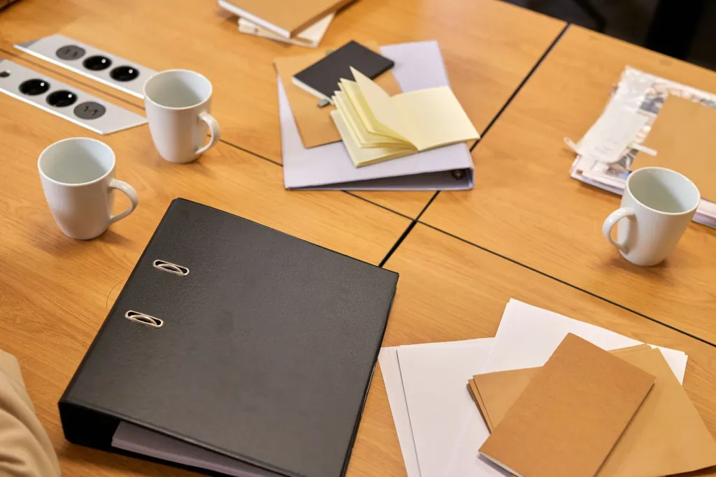 Vergadertafel met ordner, koffie en notitieblokken