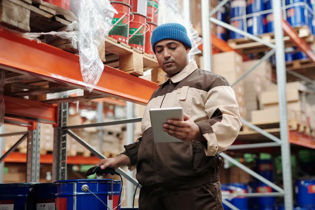 Magazijnmedewerker met een tablet tussen de stellingen